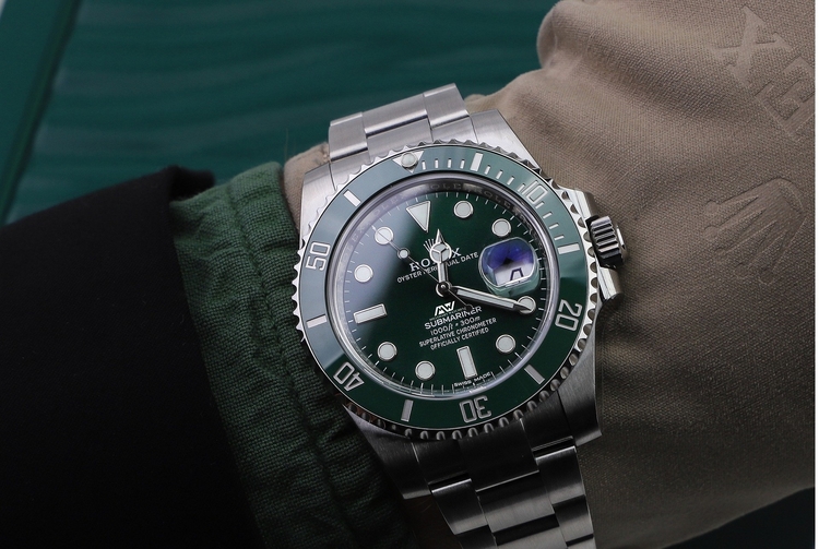 Man checking the time on a Rolex Men's watch with a green dial