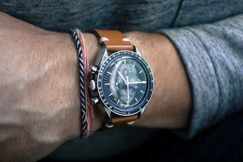 Man in casual clothing wearing an Omega dive watch with a stylish blue dial 