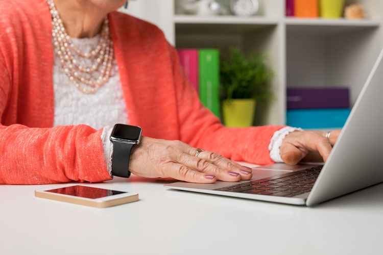 senior using smartwatch, smartphone and laptop