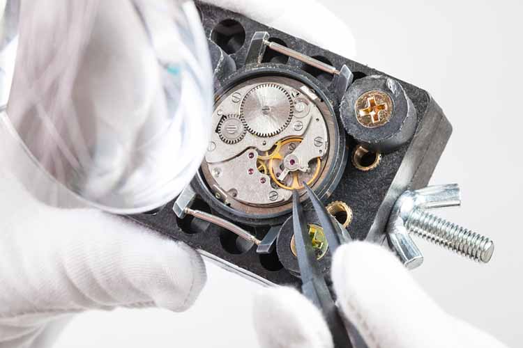 watchmaker in magnifier repairs wristwatch