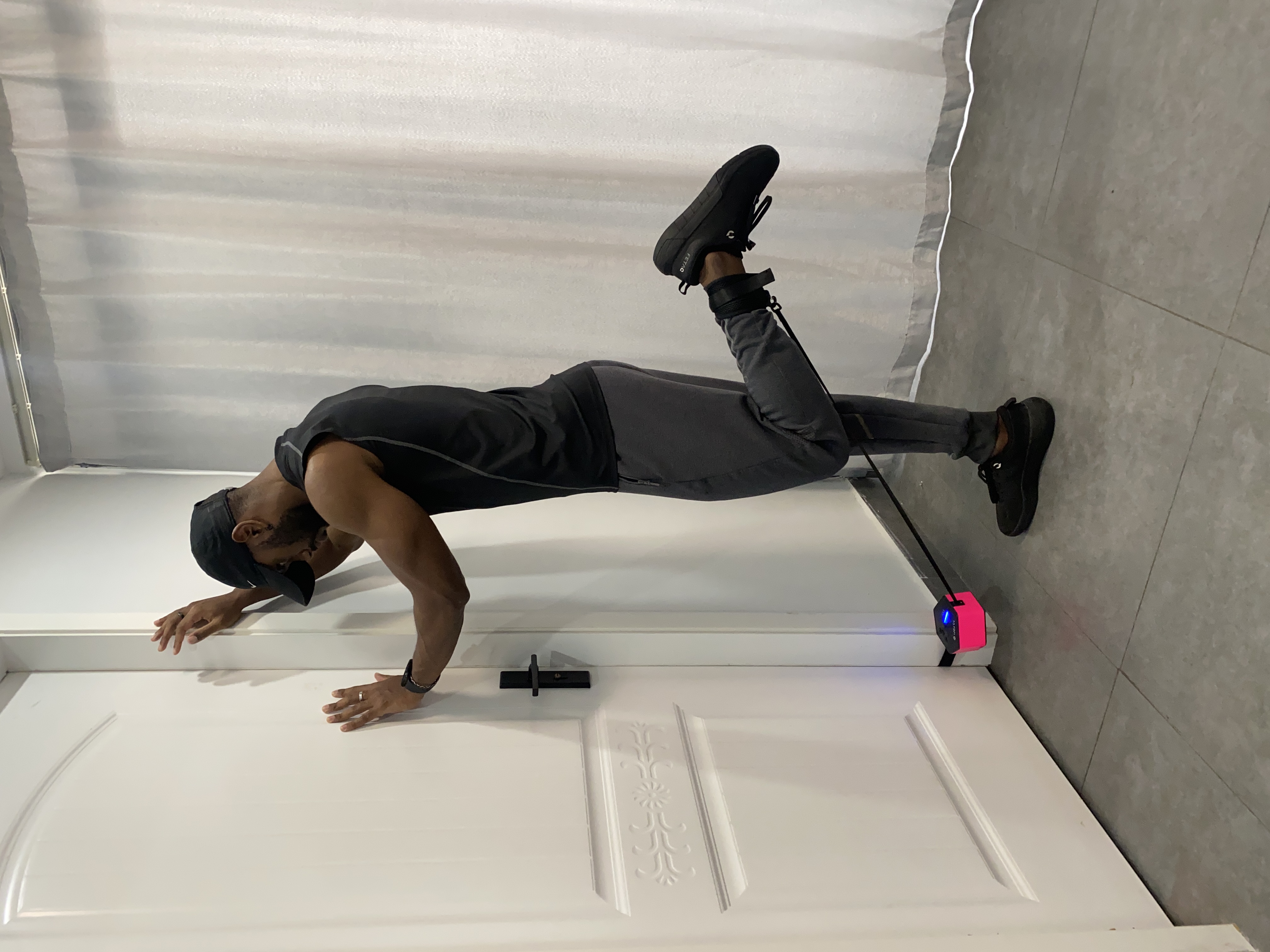 Standing hamstring curl using a Rayofi GoTone Pro anchored at the base of a door